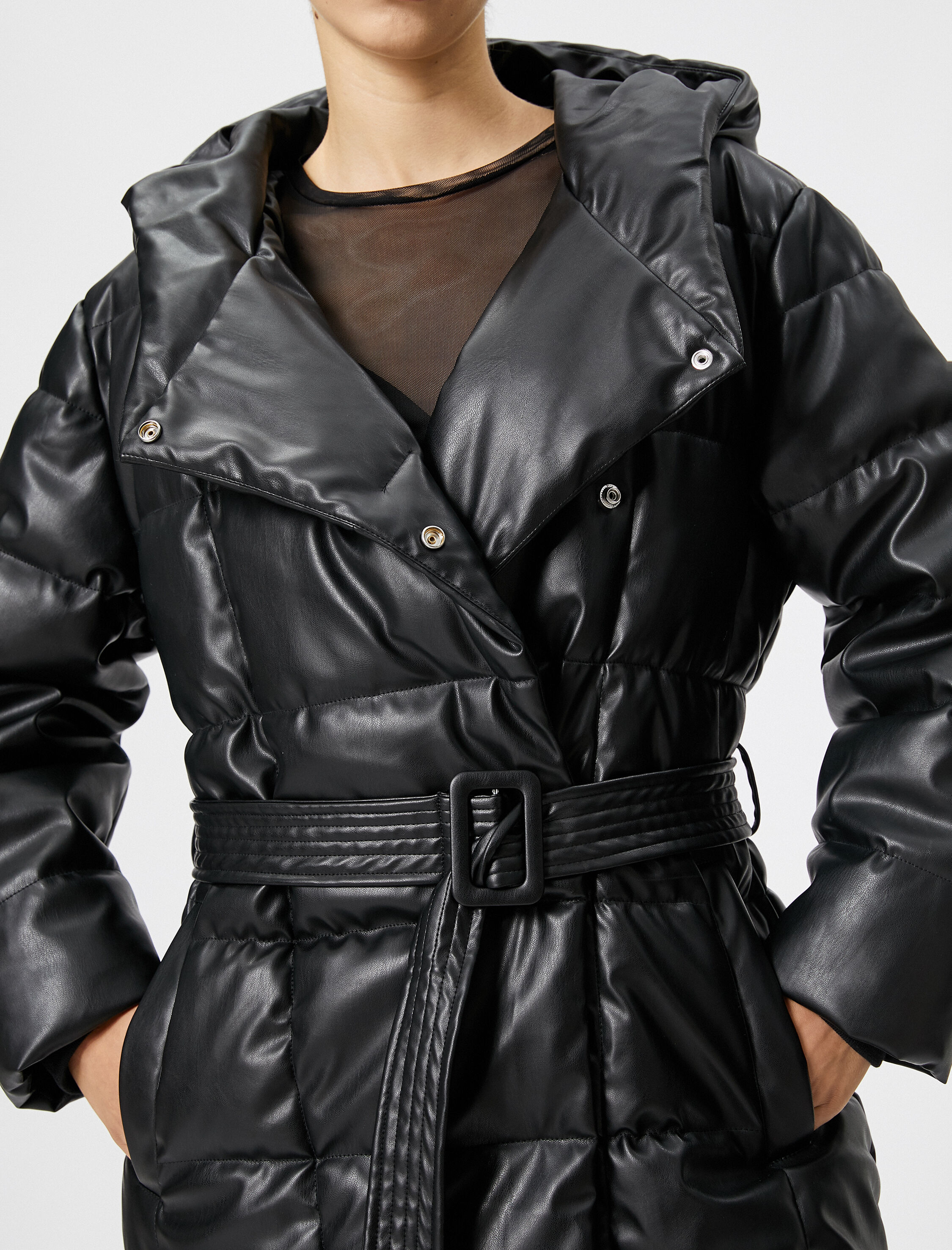   Şişme Uzun Mont Deri Görünümlü Kapüşonlu Kemer Detaylı Cepli Kapitone